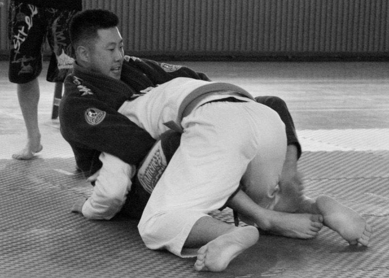 The bottom player traps one of the top player's legs in half guard during a roll.